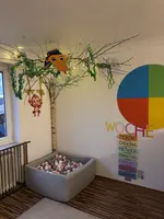 Im Bild sind ein Bällebad und ein Wochenkalender zu sehen. Bunte, freundliche, einladende Farben