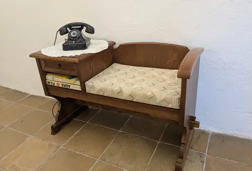 Sitzbank aus Holz, Telefon mit Wählscheibe